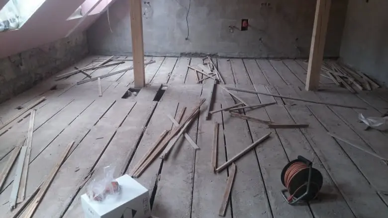 Dřevěná podlaha v rekonstrukci s roztroušenými prkny.