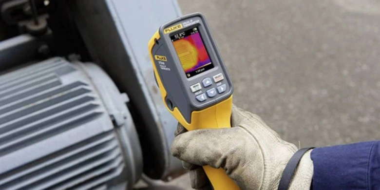 Ruční tepelná kamera měří teplotu průmyslového elektromotoru.