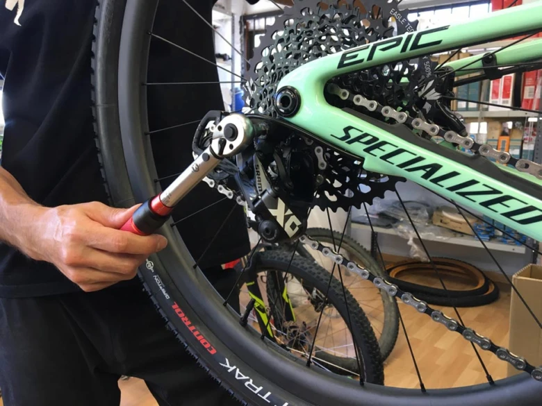 Mechanik utahuje šrouby na bicyklu pomocí momentového klíče.