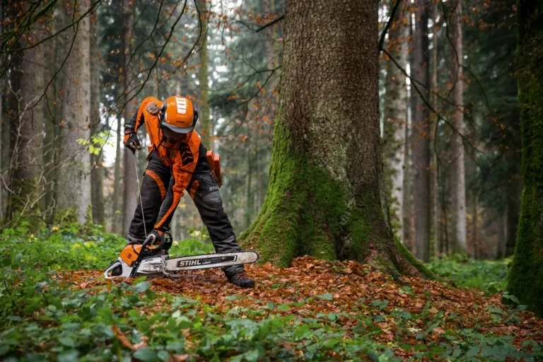 Muž v lesu používá motorovou pilu značky Stihl.