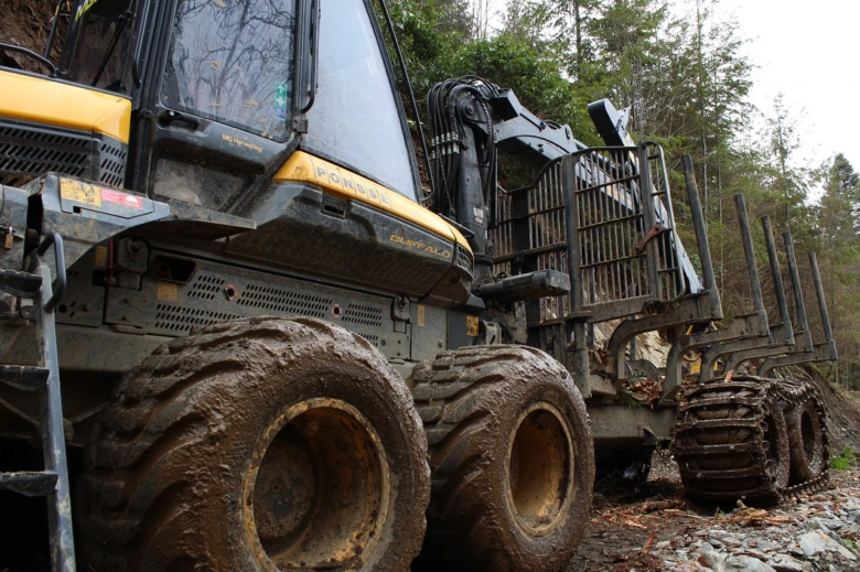 Hydraulický lesní traktor s viditelnými hydraulickými prvky v praxi.