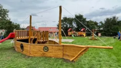 Dřevěné hřiště ve tvaru pirátské lodi na trávníku u domu.