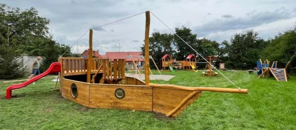 Dřevěné hřiště ve tvaru pirátské lodi na trávníku u domu.