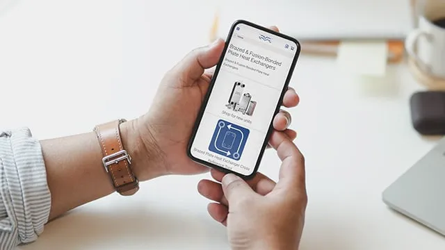 Smartphone s aplikací pro výměníky tepla v ruce.