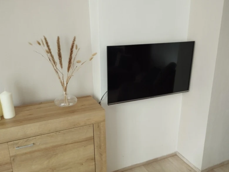 Televize zavěšená na zdi nad dřevěnou skříňkou
