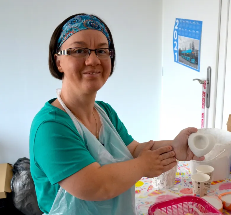 Žena drží sádrový výrobek v domovním prostředí.
