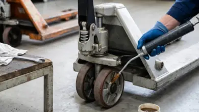 Pracovník mazí hydraulický čerpadlo paletového vozíku olejem.