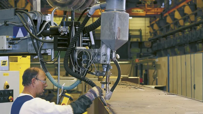 Svařák ovládá automatizovaný svařovací robota v továrně.