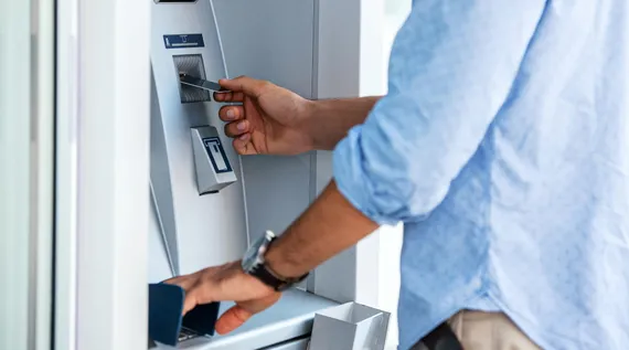 Muž vkládá svou kartou do bankomatu správným způsobem.
