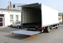 Prázdný nákladní vůz s vytaženou rampou na ulici.