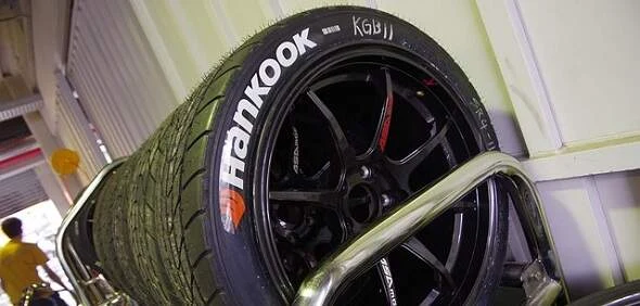Černá pneumatika značky Hankook uložená na kovovém stojanu.