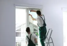 Muži odstraňují starou ochrannou folii z plastového okna.