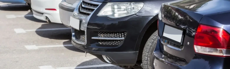 Černý automobil parkovaný v označeném místě na parkovišti.