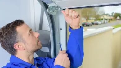 Muž upravuje mechanismus sekčních vrat pomocí klíčů.