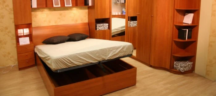 Rozkládací postel vestavěná do skříně s úložným prostorem.