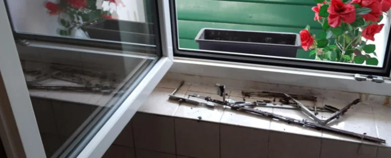 Rozbité součásti okenního mechanismu na parapetu vedle balkonových dveří.