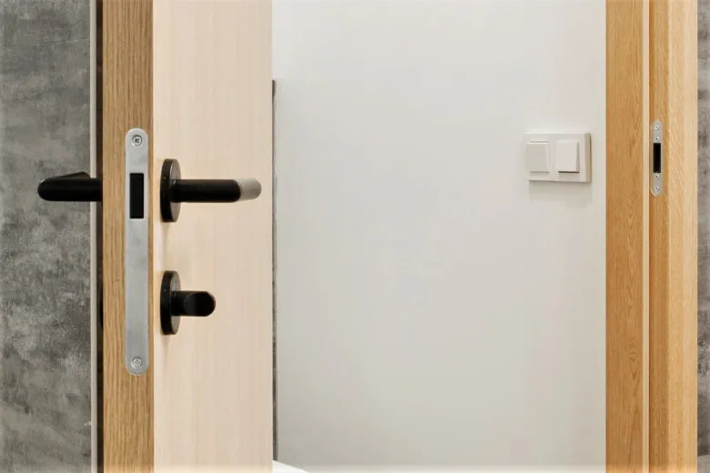 Detailní pohled na mechanismus zámku dveří s klikou a jazykem.