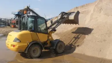 Žlutý nakladač překládá písek na staveništi.