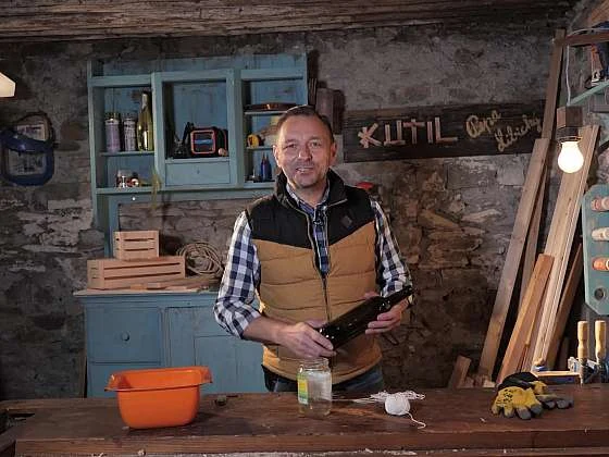 Muž drží nástroj na řezání skleněných lahví v dílně.