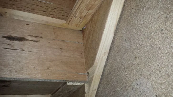 Detail dřevěného schodiště ukazující spojení kroků a nosníků.