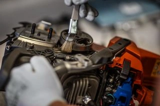 Ruční čištění vnitřních dílů motoru řetězové pily.