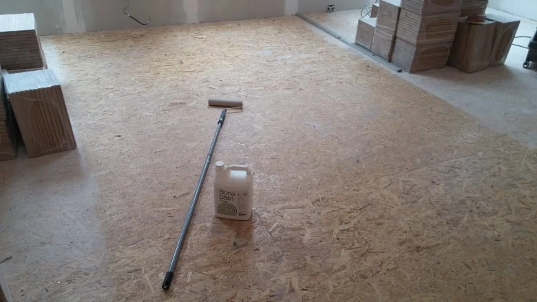Příprava podlahy na vyrovnání s válečkem lepidla a dřevěnými deskami.
