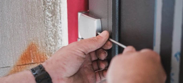 Ruční odstraňování zámku plastových dveří pomocí šroubováku.