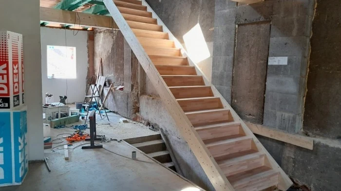 Neukončený dřevěný žebřík na půdu v místnosti při rekonstrukci.