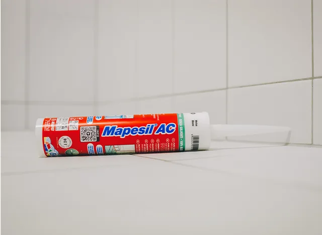 Tmlový kartáč Mapesil AC na dlažbě v koupelně.