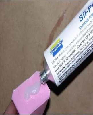Třída silikonového lepidla se nanáší na růžovou pěnovou houbu.