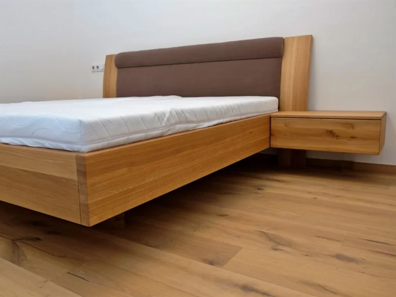 Modern dřevěná postel s matrací v ložnici pro klidný spánek.