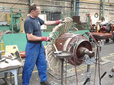 Technik převíjí vinutí na rotor elektromotoru v dílně.
