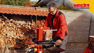 Muž používá dřevozřezovač vedle zásoby rozděleného dřeva.