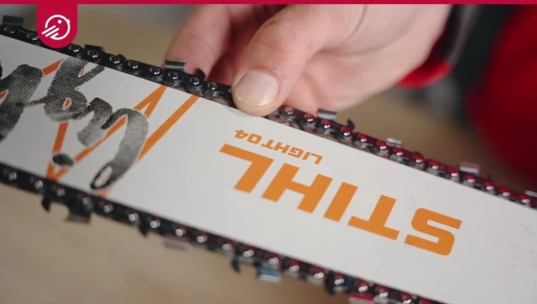 Ruka drží řetěz na liště motorové pily značky STIHL.