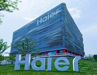Modern budova společnosti Haier s velkým logem na trávníku.