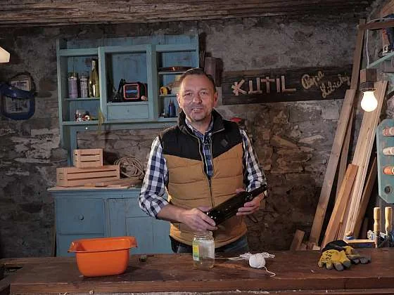 Muž drží nástroj na řezání skleněných lahví v dílně.