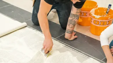 Muž nanáší lepidlo na podlahu pro pokládku linolea