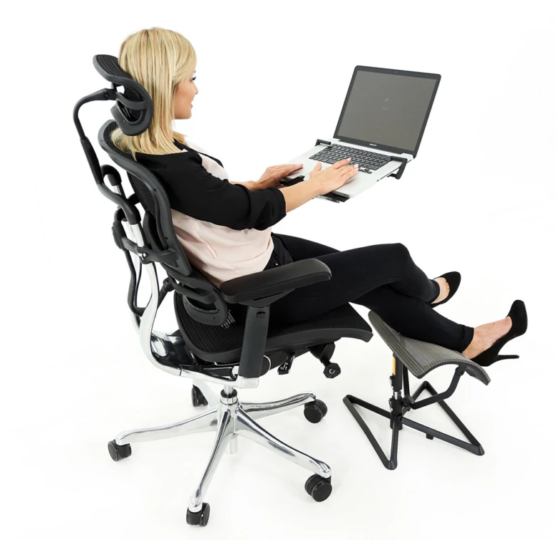 Žena sedí v ergonomické kancelářské židli s nohou na podnožce.