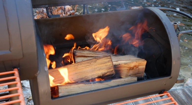 Hořící dřevo v grilu pro kouření jídla doma.