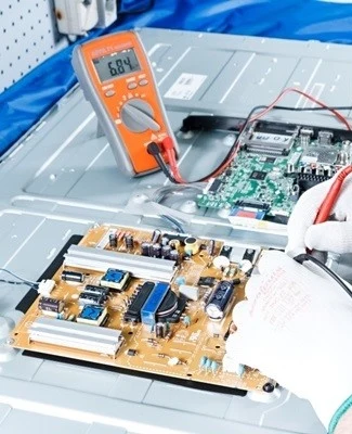 Ruční práce s elektronickými součástkami při opravě televizoru.