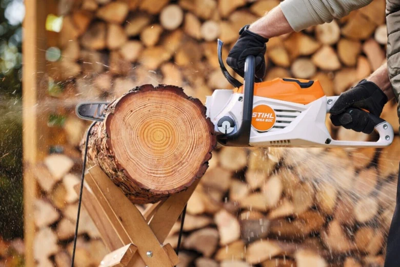 Muž řezí dřevo motorovou pilou značky Stihl s viditelným písmenem L.