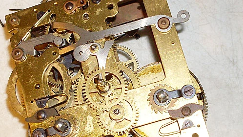 Vnitřní mechanická konstrukce starých nástěnných kyvadlových hodin s ozubenými koly.