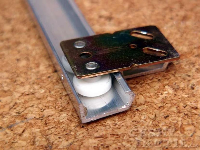 Kovový mechanism pro posuvné zásuvky s plastovými kolečky.
