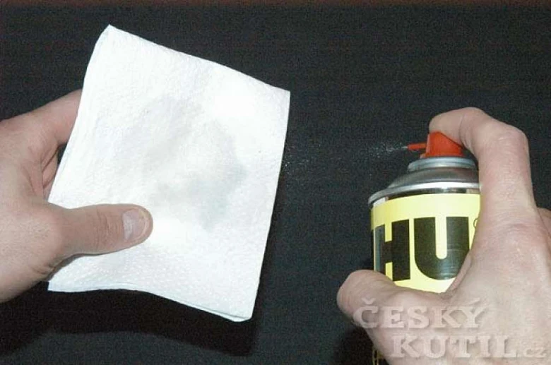 Ruce čistí povrch sprejem na ubrousek před lakováním.