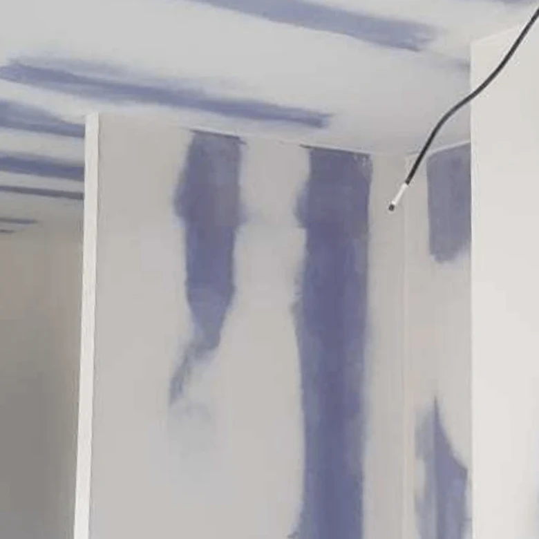 Práce s tmelem na švy omítky před broušením