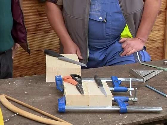 Kutil drží dřevo s jednoduchými držáky na stole.