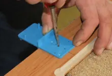 Vrtání otvorů pro panty na dřevěném nábytku pomocí modrého vodítkového nástroje.