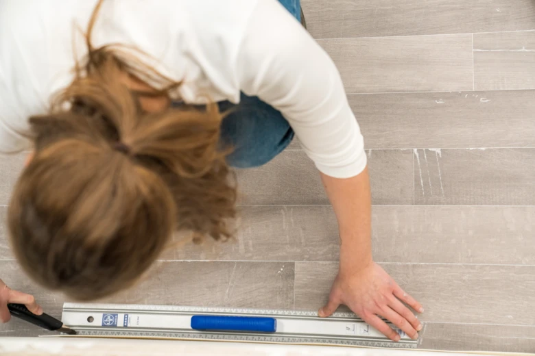 Žena měří dlažbu při pokládce linoleum nebo podlahových desek.