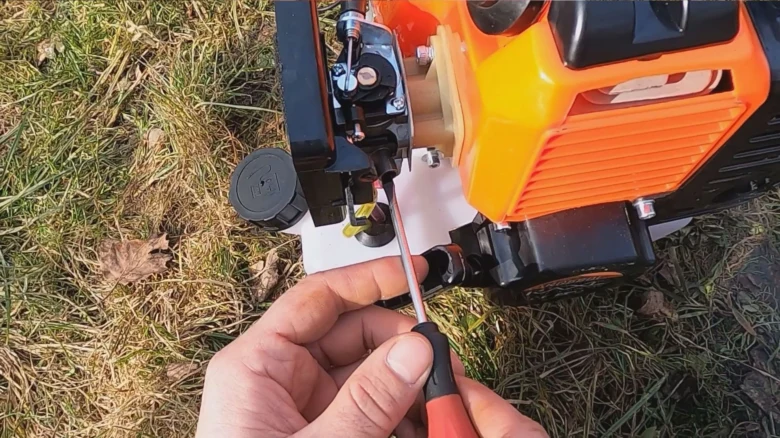 Ruční úprava karburátoru na motorové pile Husqvarna šroubovákem.