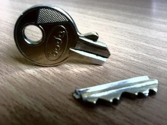 Klíč s vyjmutými páčky zamykacího válce na dřevě.